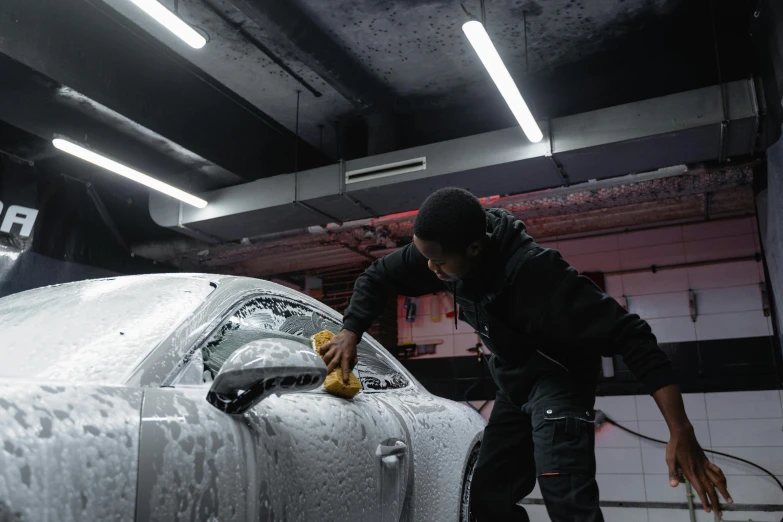 a man waxing a car in a garage, by An Gyeon, pexels contest winner, afro tech, white foam, avatar image, **cinematic