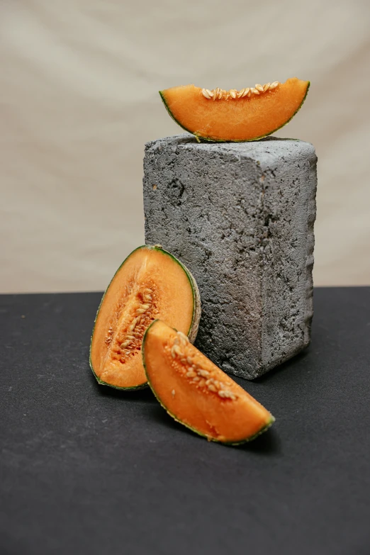 a piece of melon sitting on top of a block of cement, a still life, by Jacob Burck, unsplash, renaissance, made of lava, (light orange mist), detailed product shot, harvest