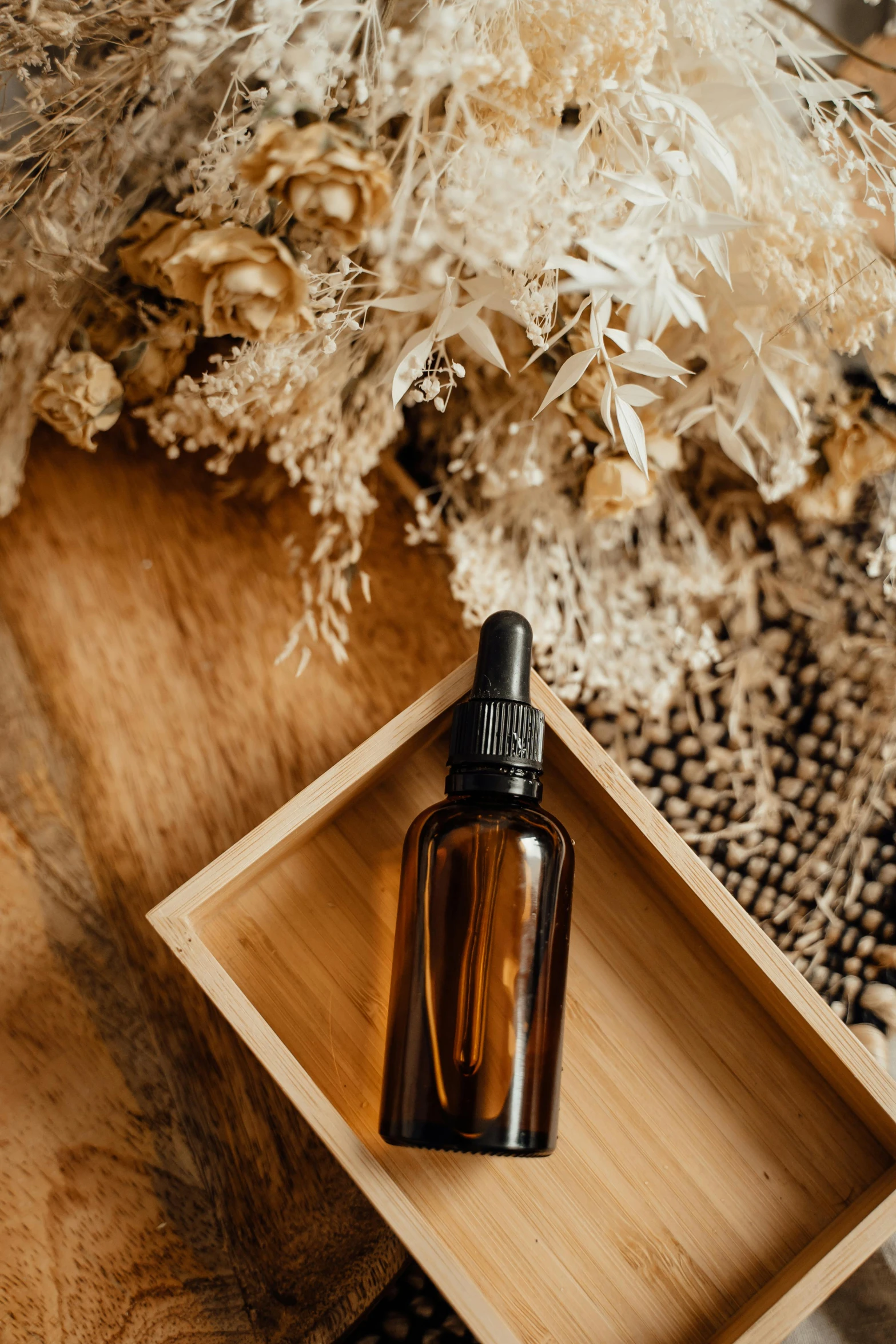 a bottle of essential oil sitting on top of a wooden box, by Robbie Trevino, dried flowers, thumbnail, brown, sleek