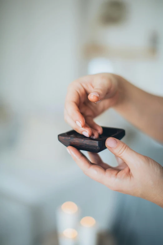 a close up of a person holding a cell phone, bog oak, partially cupping her hands, holding a battery, dark chocolate hair colour