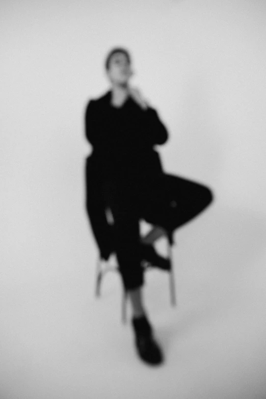 a black and white photo of a woman sitting on a chair, unsplash, conceptual art, blurry footage, androgyny, photograph ”, on a pale background