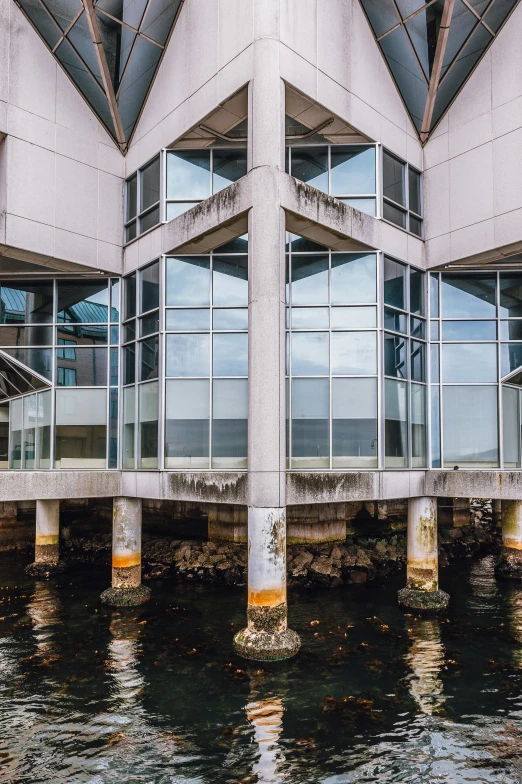 a building sitting on top of a body of water, unsplash, brutalism, broken panes of glass, 2 5 6 x 2 5 6 pixels, docks, okinawa churaumi aquarium