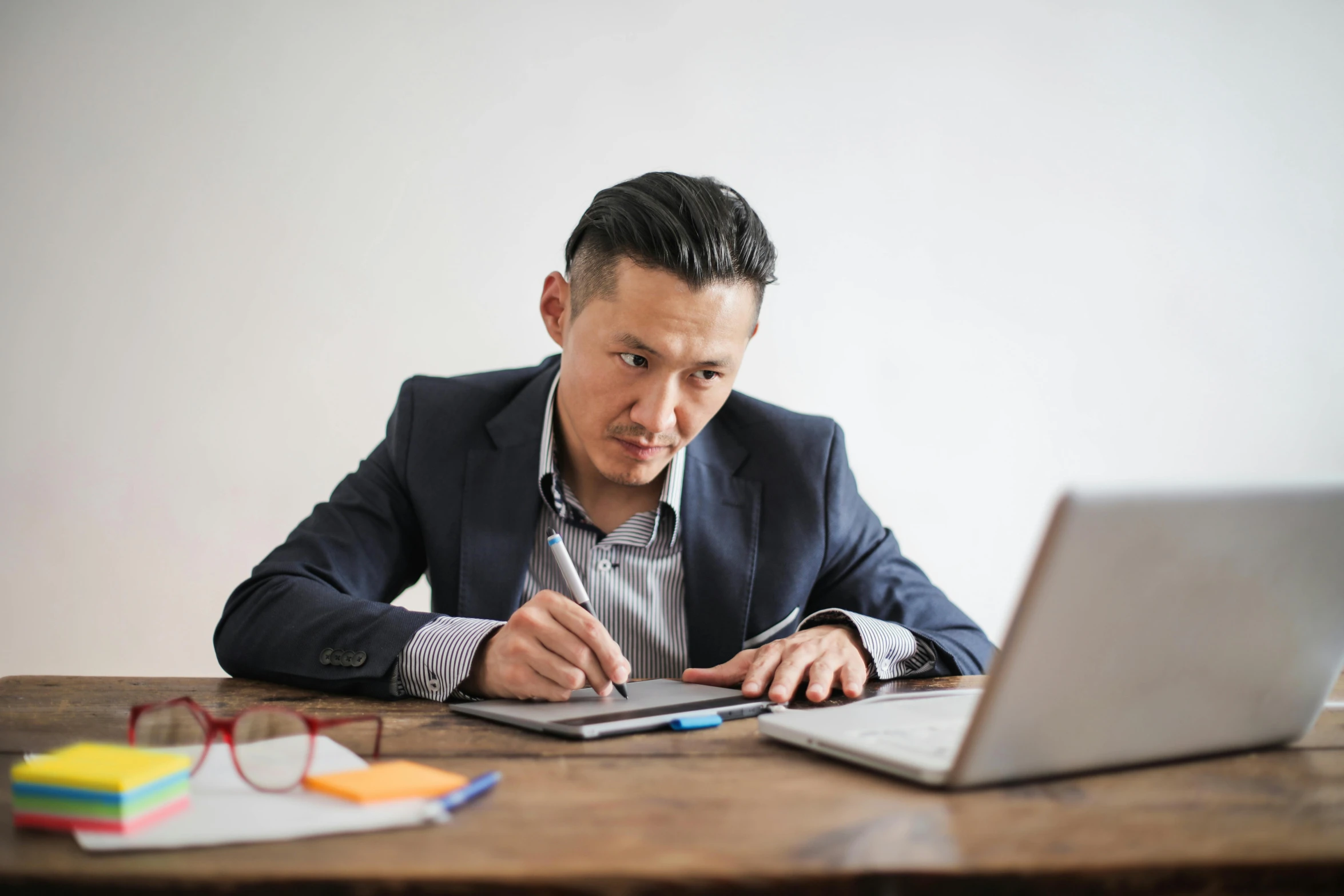 a man sitting at a table in front of a laptop, by Carey Morris, pexels, hideki anno, holding pencil, lachlan bailey, thumbnail