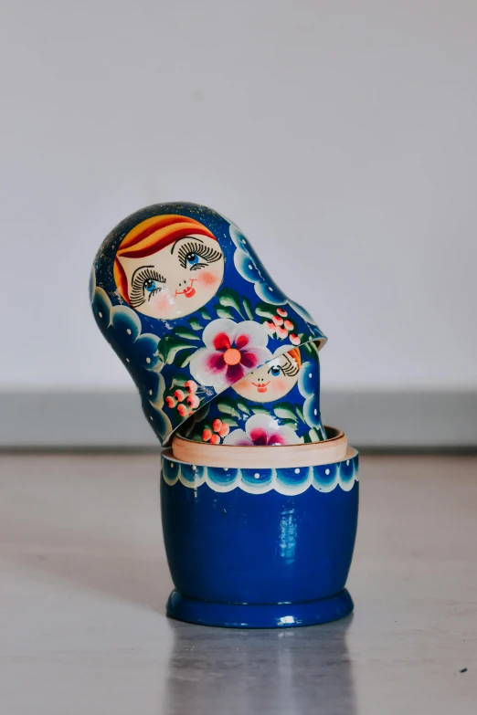 a close up of a matry doll on a table, by Miroslava Sviridova, unsplash, folk art, dipped in polished blue ceramic, clogs, multicolored, high angle close up shot