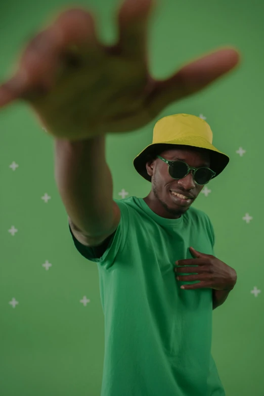 a man in a green shirt and a yellow hat, inspired by Ay-O, trending on pexels, young thug, green screen, dark skinned, triumphant pose