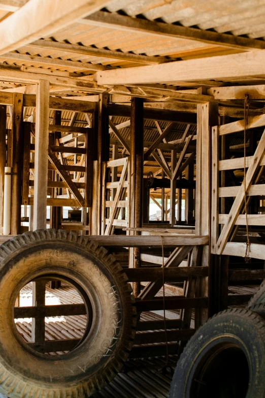 a pile of tires sitting on top of a wooden floor, by Peter Churcher, unsplash, inside a farm barn, in the australian outback, truss building, some stalls