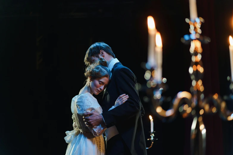 a man and a woman standing next to each other, by Alice Mason, pexels contest winner, romanticism, theatrical lighting, candles in foreground, tuomas korpi and wlop, embracing