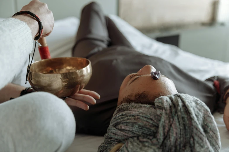 a man laying on top of a bed next to a woman, by Julia Pishtar, pexels contest winner, mortar and pestle, kundalini energy, holding a bell, music being played