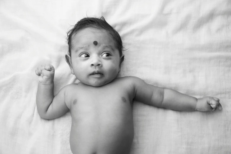 a black and white photo of a baby, by Sunil Das, pexels, third eye middle of forehead, tummy, surprised, nuri iyem