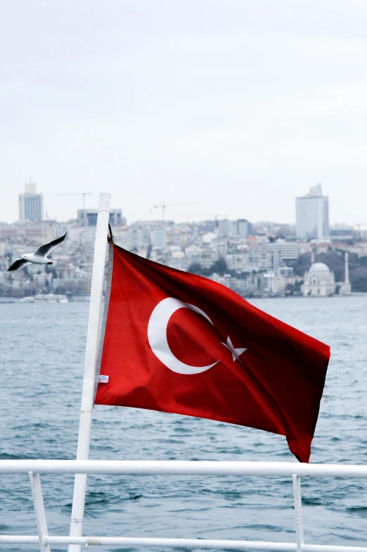 a red and white flag flying over a body of water, by Nazmi Ziya Güran, slide show, istanbul, avatar image