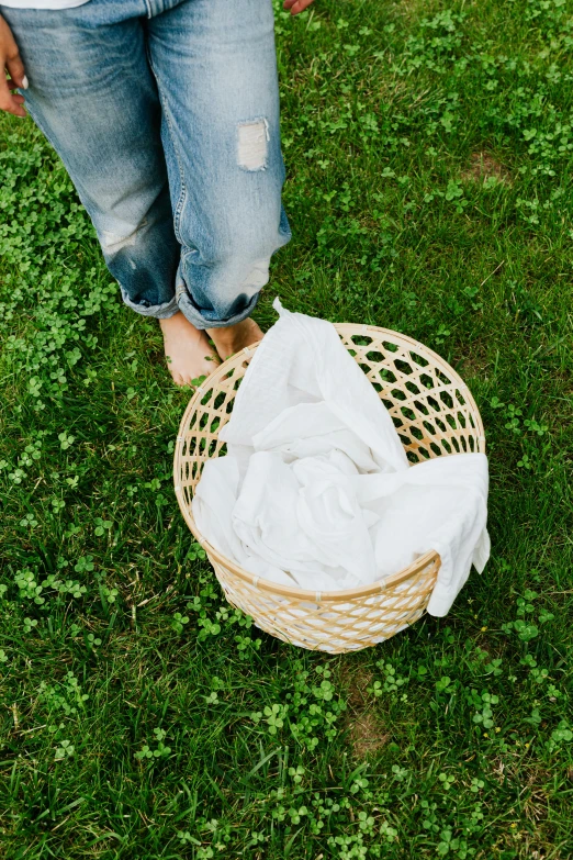 a woman standing on top of a lush green field, dirty clothes, with an easter basket, wearing white shirt, sustainable materials