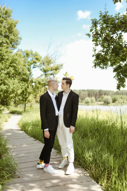 a couple of men standing on top of a wooden walkway, white suit and black tie, queer, minn, in a scenic environment