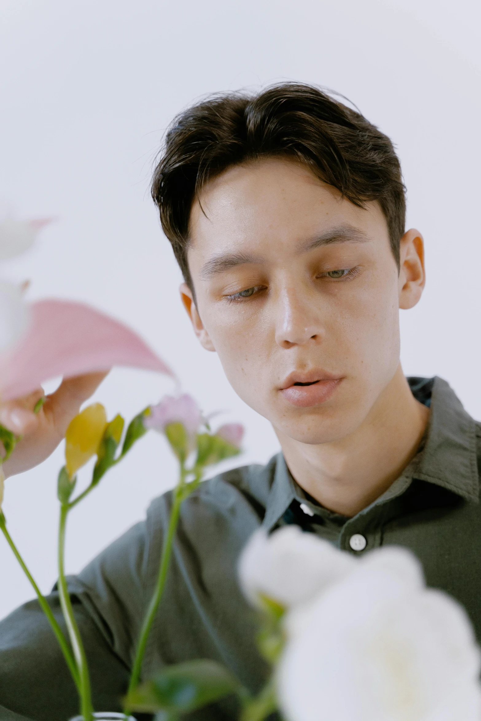 a man sitting at a table with flowers in front of him, an album cover, inspired by Fei Danxu, trending on unsplash, hyperrealism, sharp cheekbones, youtube video screenshot, still frame from a movie, picking up a flower