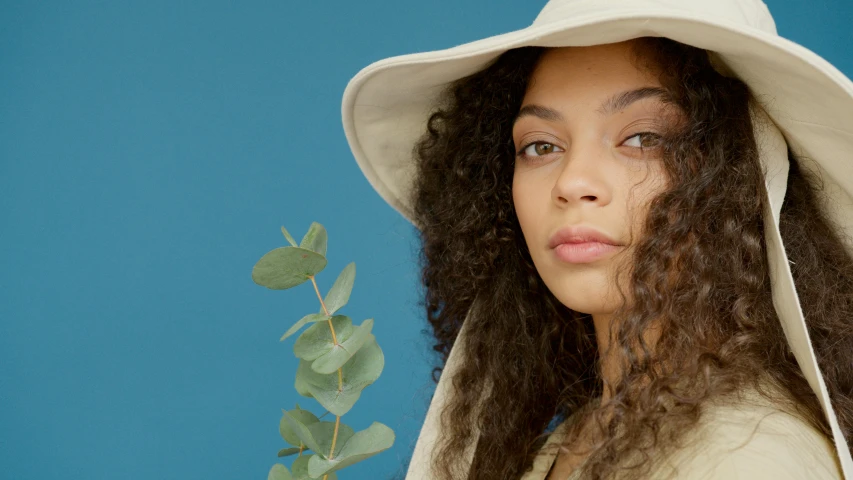 a woman with curly hair wearing a white hat, trending on pexels, charli bowater and artgeem, botanicals, beauty campaign, bucket hat