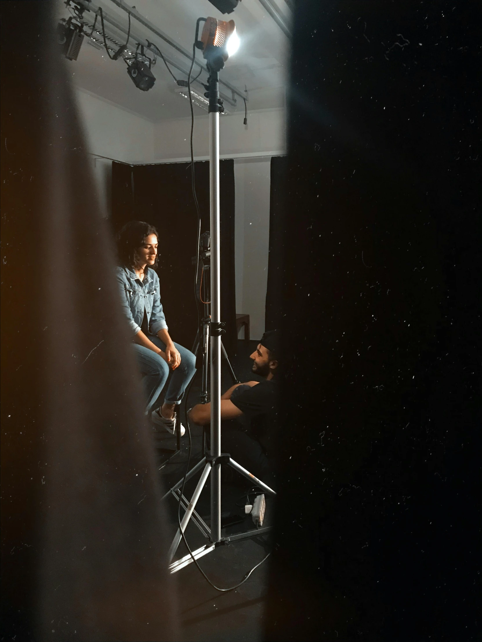 a man sitting on a chair in front of a camera, in the space, lighting her with a rim light, production ig studios, full body 8k