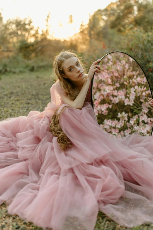 a woman in a pink dress sitting in front of a mirror, a picture, inspired by Oleg Oprisco, unsplash contest winner, renaissance, wearing a pink romantic tutu, nature outside, flowing gown, sydney sweeney