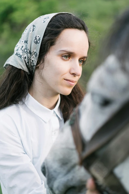 a woman standing next to a horse in a field, an album cover, inspired by Vasily Perov, trending on unsplash, renaissance, bandana, movie scene portrait closeup, beautiful jewish woman, wearing a light shirt