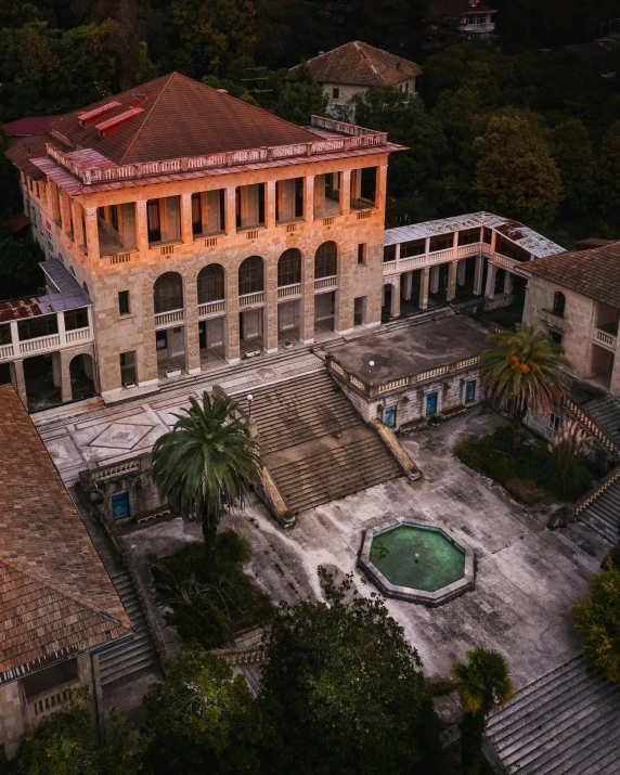 a large building sitting on top of a lush green hillside, an album cover, pexels contest winner, renaissance, greek pool, school courtyard, drone photo, 1910s architecture