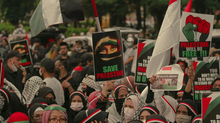 a large group of people holding up signs, a colorized photo, by Julia Pishtar, shutterstock, hurufiyya, red and black flags waving, with a covered face, album art, square