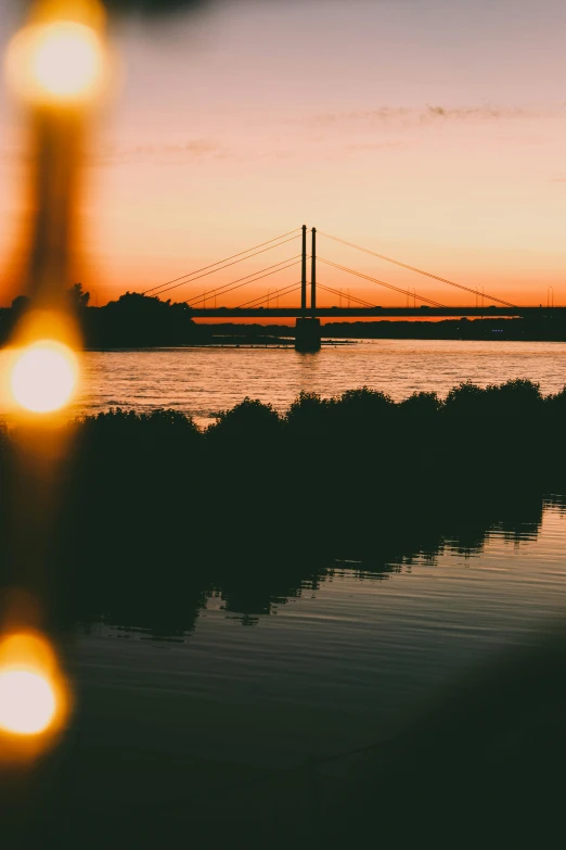 a body of water with a bridge in the background, by Jan Tengnagel, pexels contest winner, warm glow, viewed from a distance, detailed silhouette, zoomed in shots