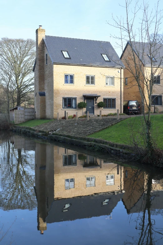 a couple of houses sitting next to a body of water, a photo, by Jan Cox, brockholes, mixed development, reflective water koi pond, cream