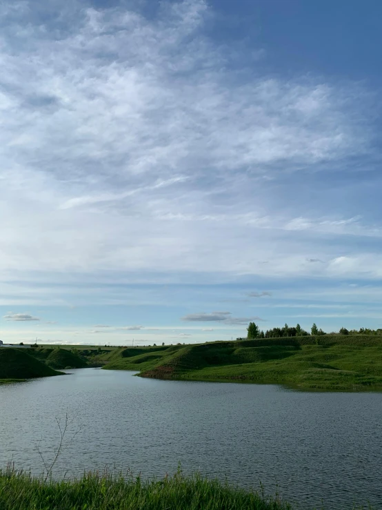 a body of water sitting on top of a lush green field, hurufiyya, near a lake, surrounding the city, 2019 trending photo, photo on iphone