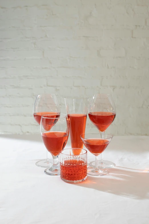 a group of wine glasses sitting on top of a table, inspired by Jacopo Bellini, renaissance, coral red, various sizes, bubbles, tall iced tea glass