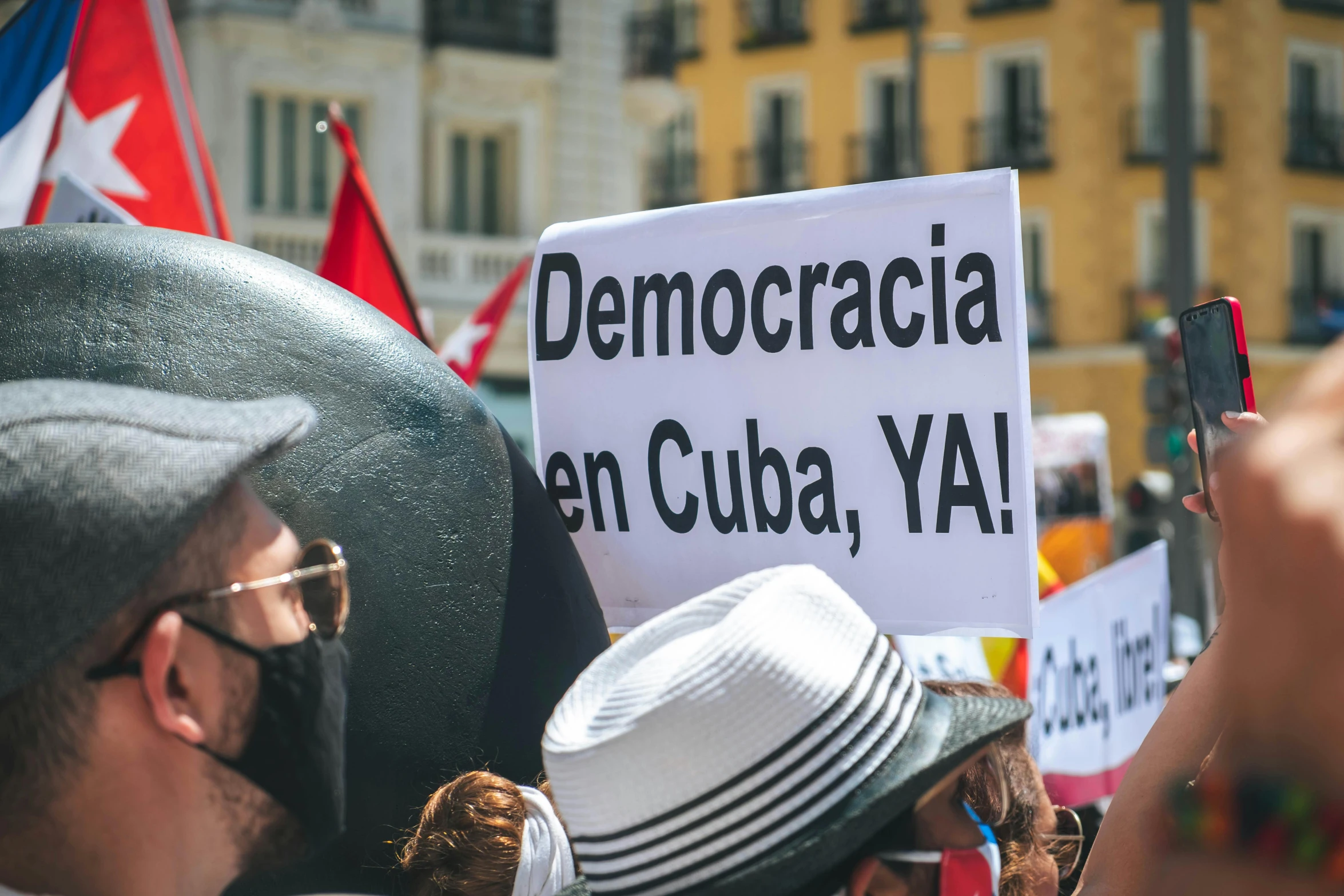 a group of people holding signs in front of a building, by Luis Molinari, verdadism, wearing sunglasses and a hat, politica, more, square