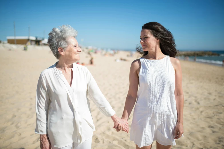 two women walking on a beach holding hands, a portrait, pexels contest winner, renaissance, older woman, bright white light, lesbian, summer street