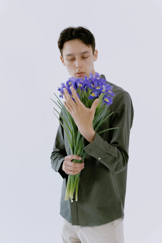 a man holding a bunch of purple flowers, an album cover, inspired by Fei Danxu, b - roll, male model, surprising, ( ( theatrical ) )