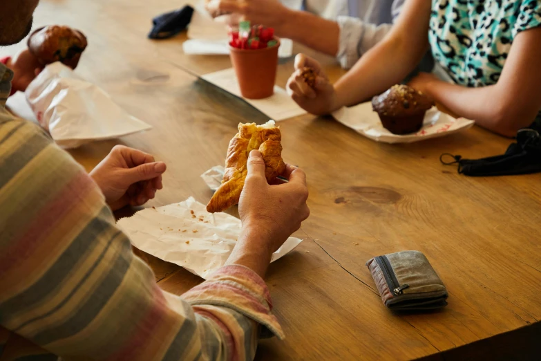 a group of people sitting at a table eating food, by Jessie Algie, unsplash, process art, pastries, the handbag is over a wood table, 15081959 21121991 01012000 4k, bakery