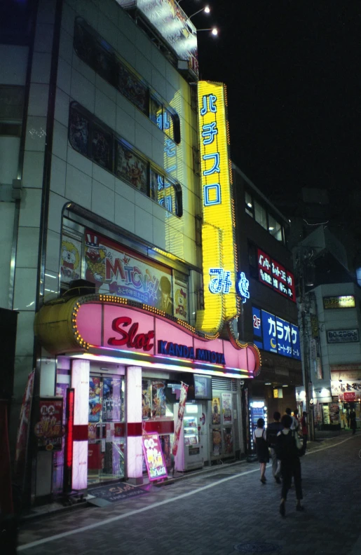 a group of people walking down a street at night, inspired by Tadanori Yokoo, flickr, convenience store, exterior view, neon tokyo, an old cinema