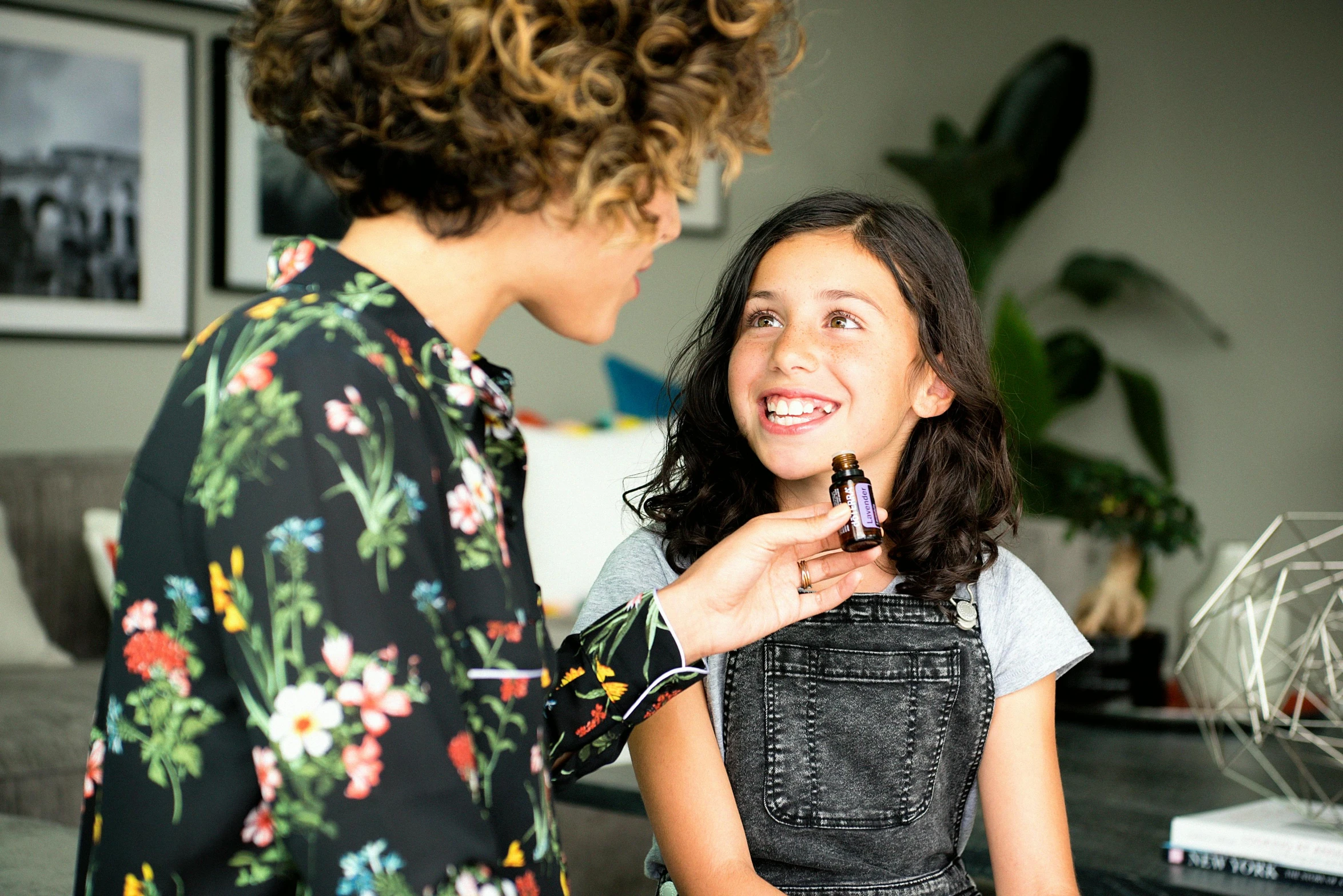 a woman standing next to a woman in a living room, by Julia Pishtar, pexels contest winner, vibrant vials, happy kid, manuka, holding an epée