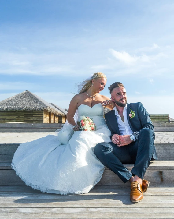 a bride and groom sitting on some steps, a photo, by Liza Donnelly, pexels contest winner, maldives in background, blue skies, smug look, wooden platforms