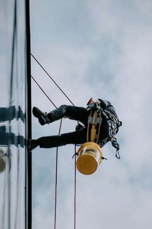 a man hanging from the side of a tall building, pexels contest winner, cleaning future, worksafe. cinematic, profile image, black