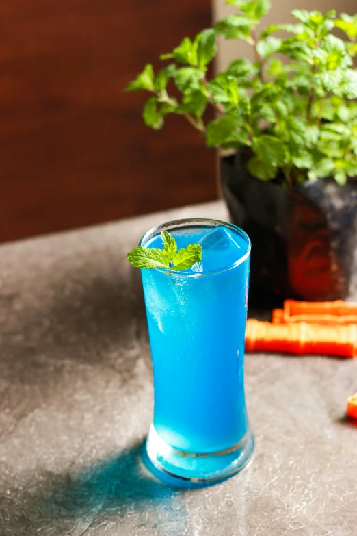 a blue drink sitting on top of a table next to carrots, mint, full product shot, iconic shot, ((blue))