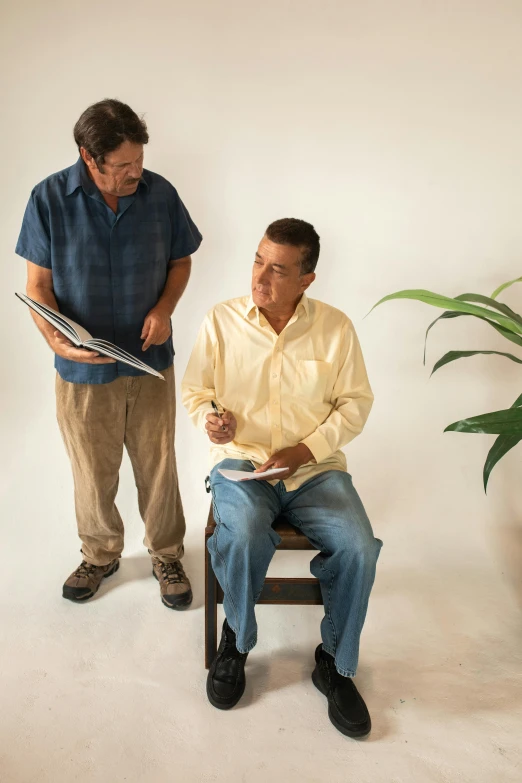 a man sitting on a chair next to another man, visual art, hispanic, standing posture, screenwriter, environmental