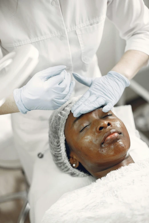 a woman getting a facial treatment at a beauty salon, by Daniel Lieske, black scars on her face, silicone skin, thumbnail, brown