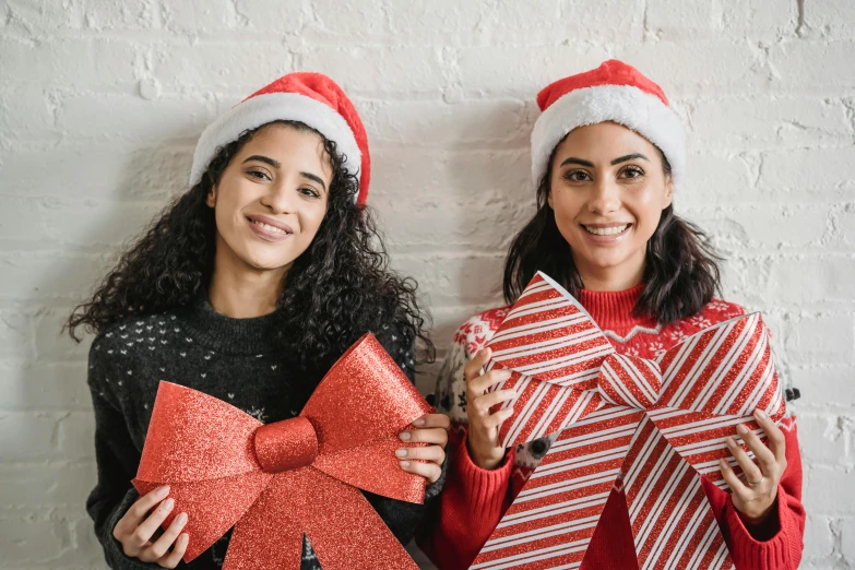 two women standing next to each other holding christmas presents, pexels contest winner, hurufiyya, a red bow in her hair, santa's workshop, sirius a and sirius b, brunettes