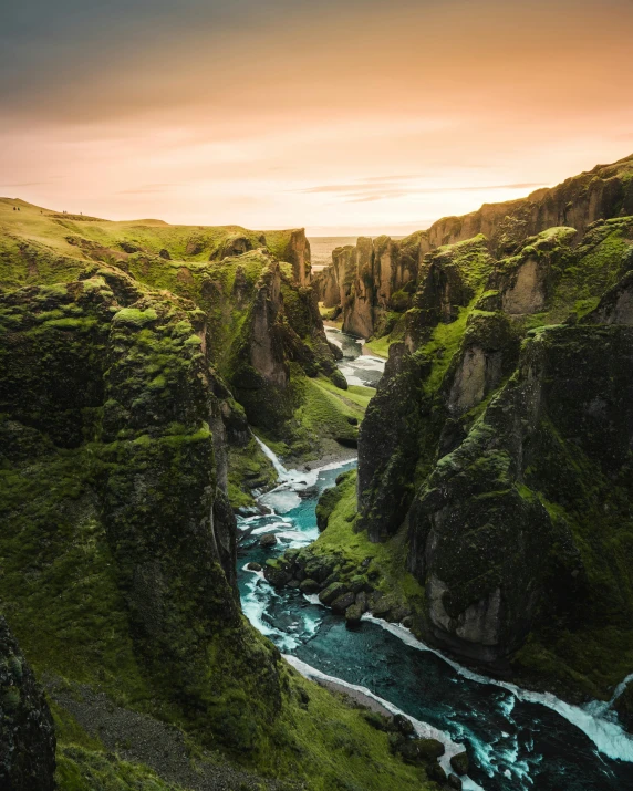 a river flowing through a lush green valley, by Johannes Voss, pexels contest winner, hurufiyya, tall stone spires, sundown, chasm, conde nast traveler photo