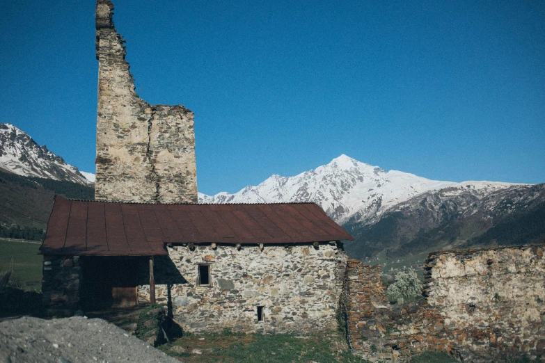 a stone building in front of a mountain range, by Muggur, pexels contest winner, rusty metal towers, 1900s photo, white, georgic