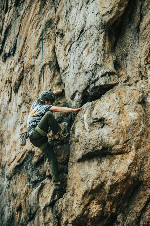 a man climbing up the side of a cliff, pexels contest winner, wearing adventure gear, soft texture, low colour, sport