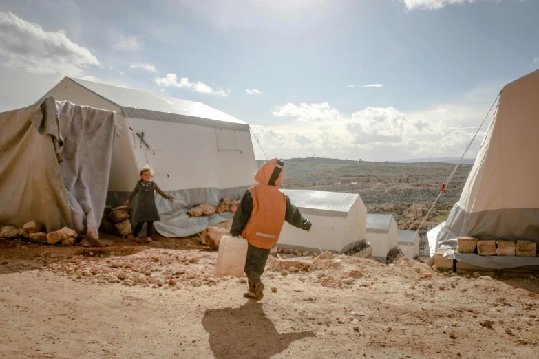 a little boy that is standing in the dirt, by Simon Marmion, temporary art, white buildings with red roofs, tents, jordan, view from the side