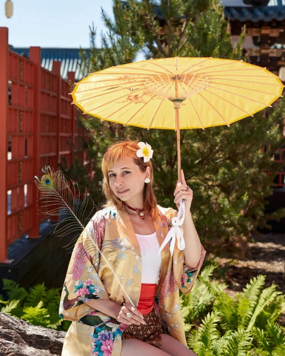 a woman sitting on a rock holding a yellow umbrella, a portrait, inspired by Nishikawa Sukenobu, unsplash, felicia day, wearing seashell attire, in japanese garden, 2000s photo