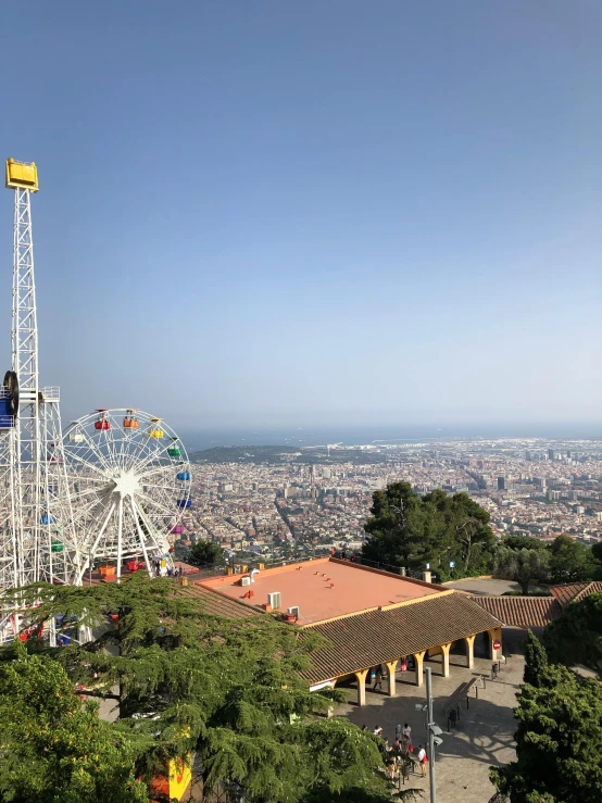 a view of a ferris wheel from the top of a hill, monserrat gudiol, city buildings on top of trees, high res 8k, photo on iphone