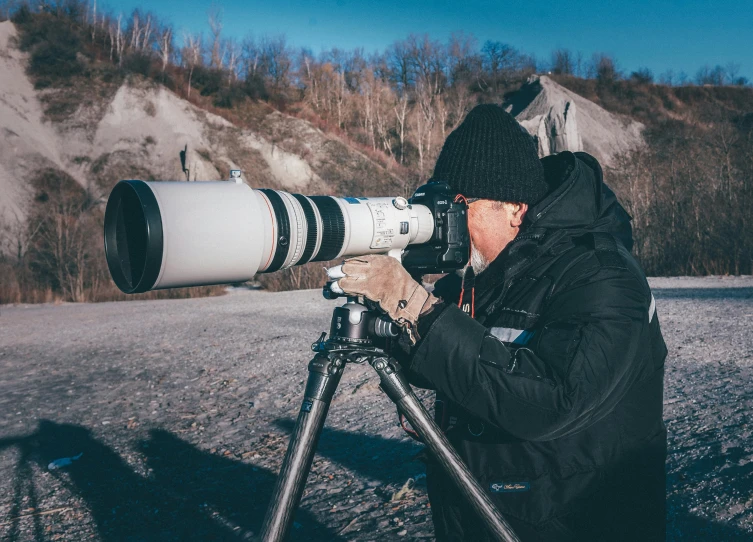 a man with a camera on a tripod, by Adam Marczyński, pexels contest winner, 5 0 0 mm tele lens, extreme long shot, telephoto, shot with hasselblade camera