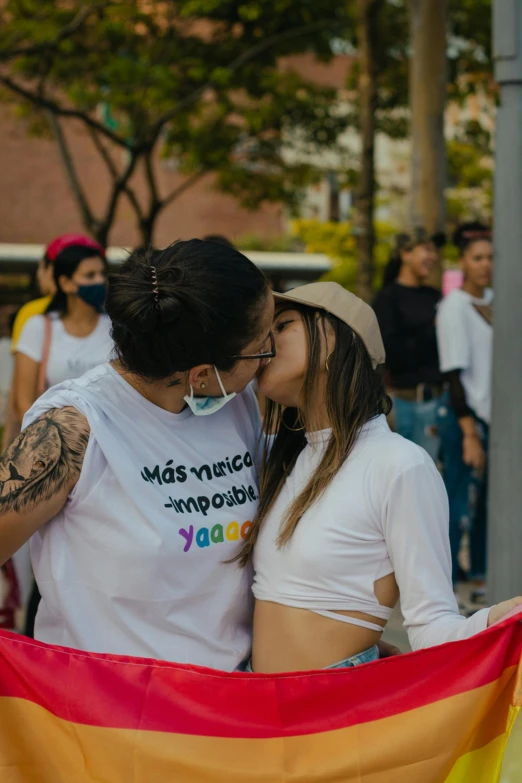 a couple kissing each other while holding a rainbow flag, a cartoon, trending on pexels, graffiti, colombia, woman holding another woman, 🚿🗝📝, latino