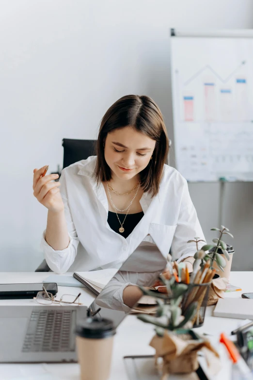 a woman sitting at a desk in front of a laptop, pexels contest winner, wearing lab coat and a blouse, gif, studious, business