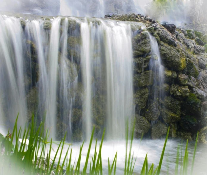 a waterfall in the middle of a lush green forest, a picture, by Jan Rustem, hurufiyya, wet grass and stones, botanic garden, waterfall falling into a lake, bamboo