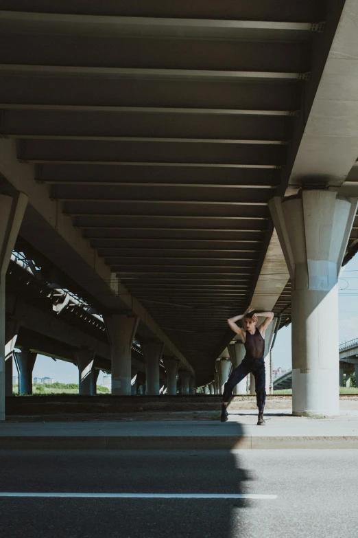 a person riding a skateboard under a bridge, an album cover, by Carey Morris, unsplash, happening, ballet pose, wide long view, model standing pose, highway